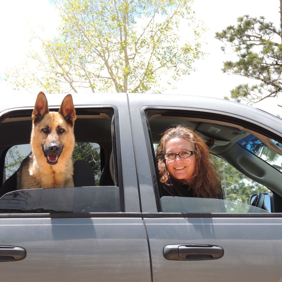 Dog Mom and her Fur Baby look out car window, smiling